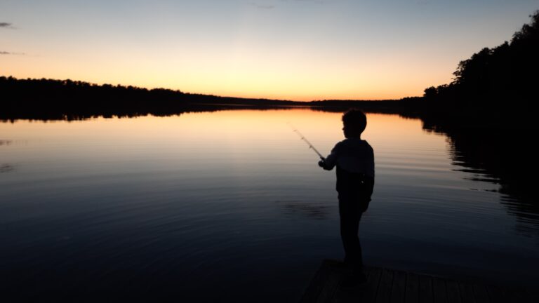 Barn som fiskar i sjö i solnedgång